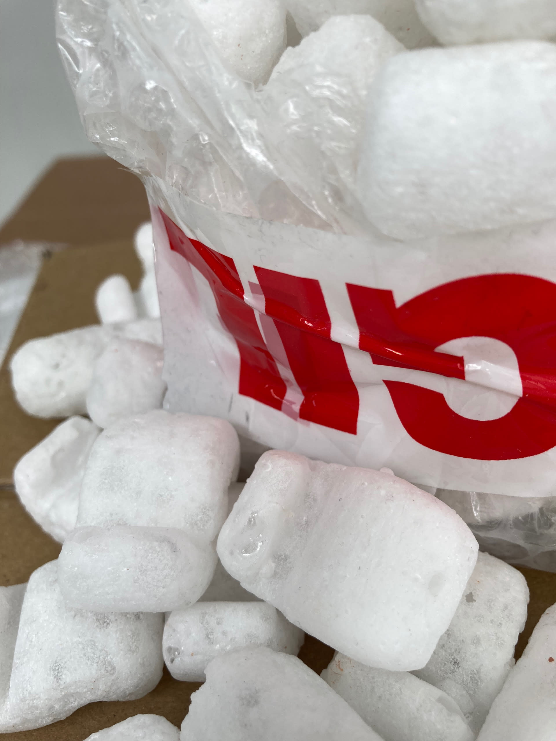 detail of white foam glass packing peanuts and corner of bubble wrap box with upside-down fragile packing tape 