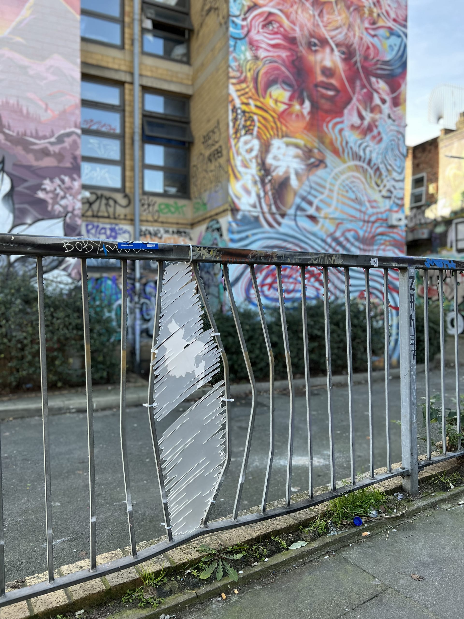 Gap in railings filled with a frosted acrylic laser cut shape of a scribble to emulate graffiti. Object has image of Bangladesh 