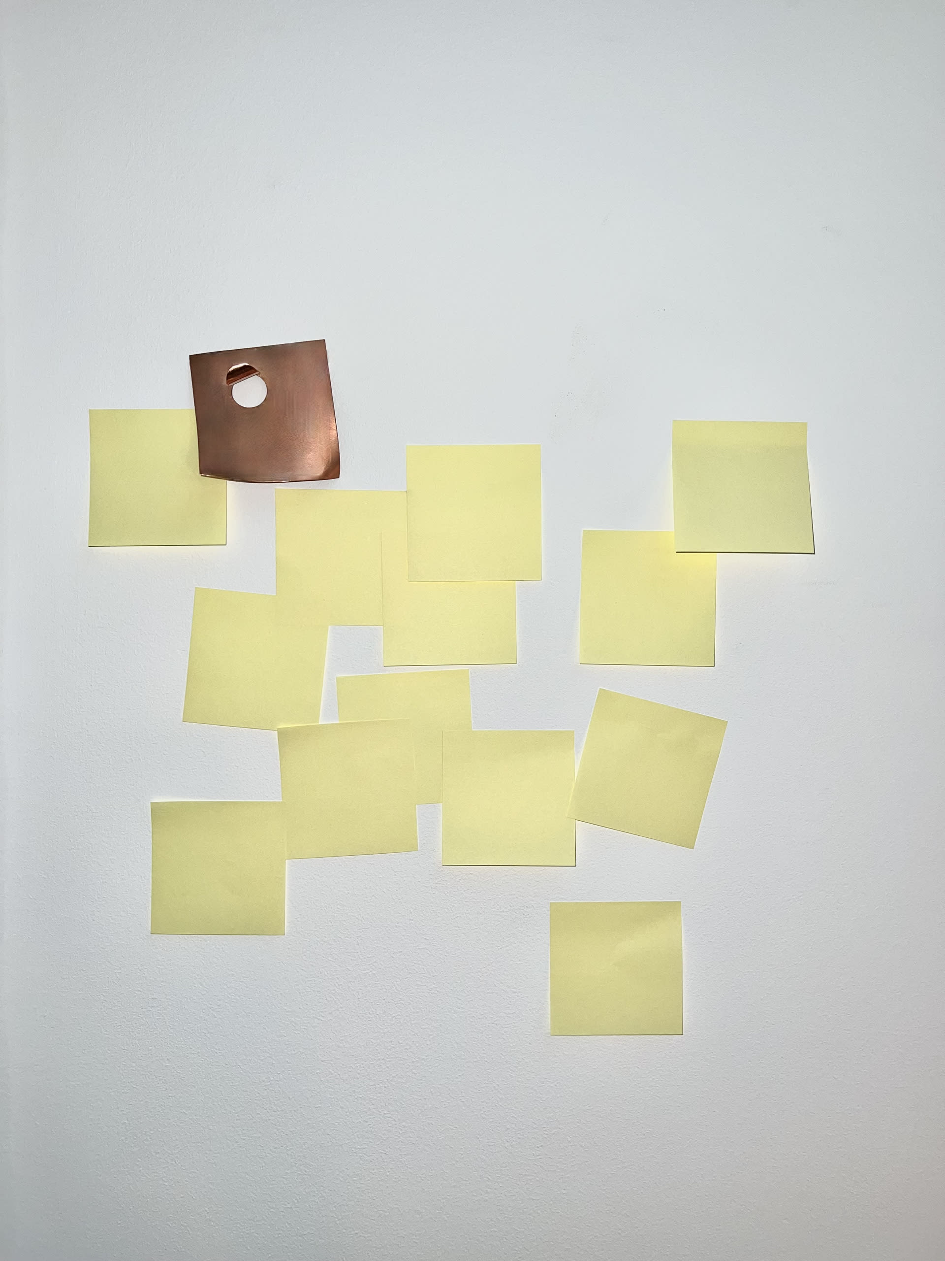 Copper sticky note amidst a wall covered in yellow sticky notes