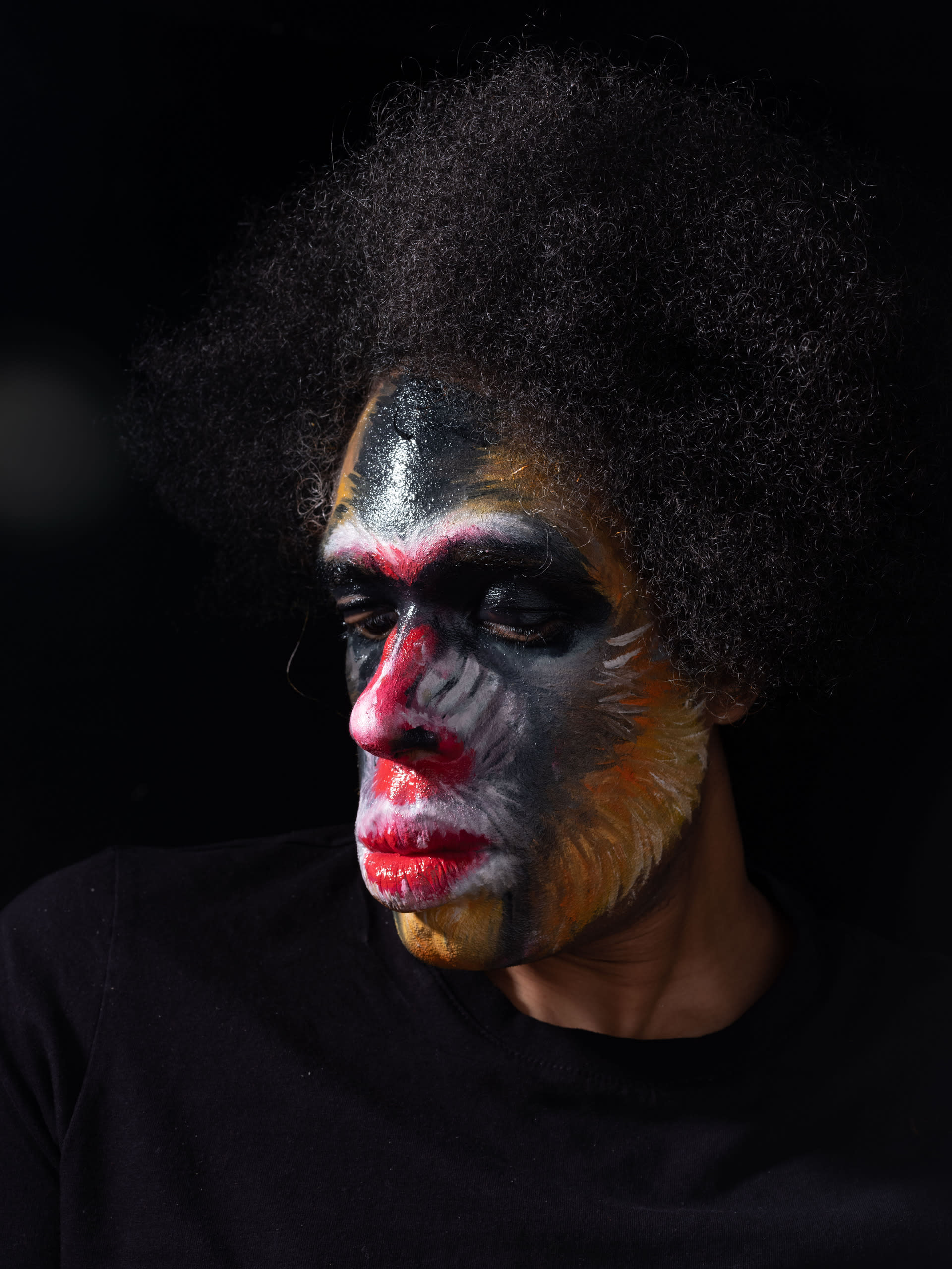 A photograph of myself, face paint as a Mandrill, in a black background