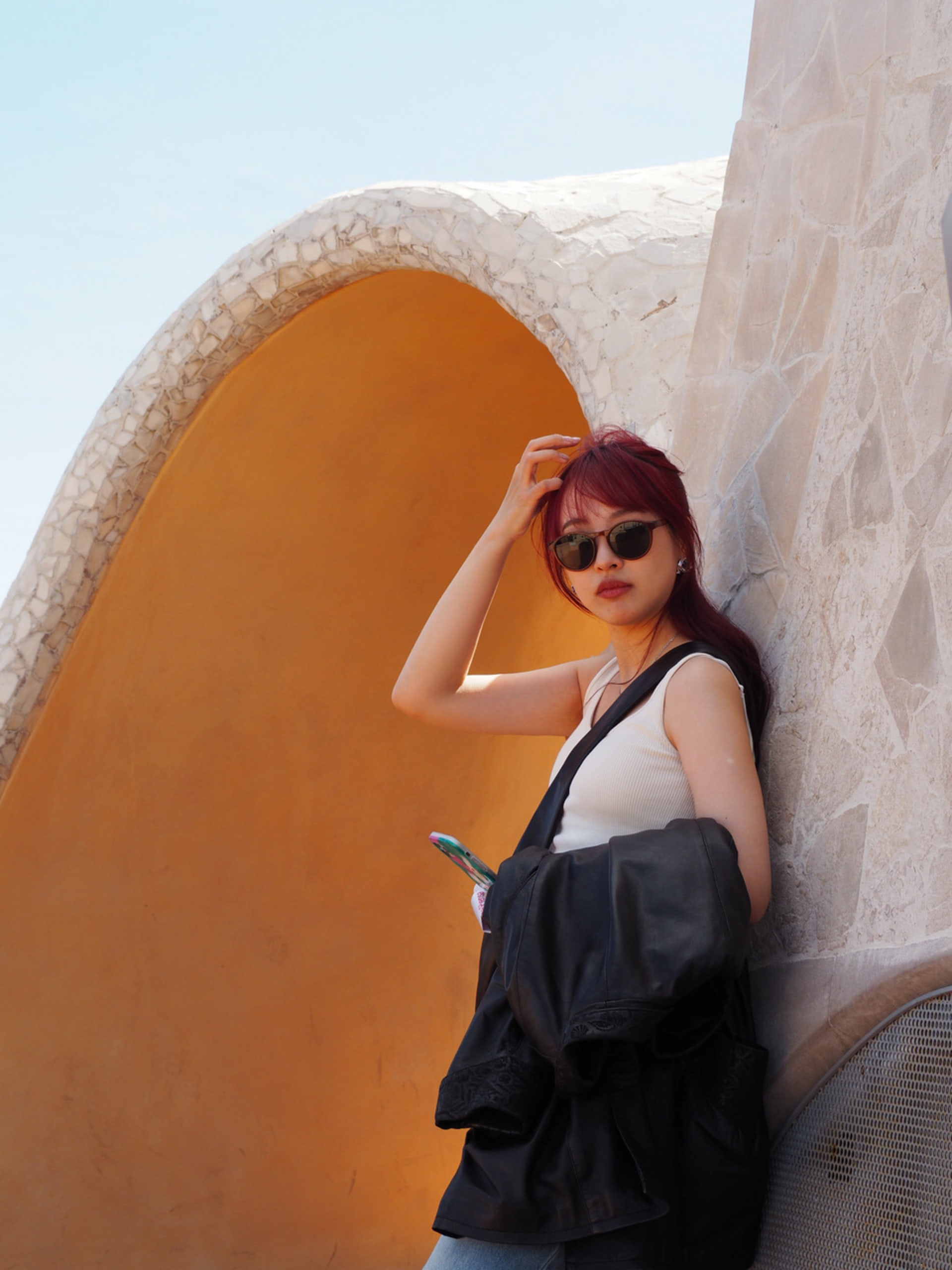 A long-haired girl wearing sunglasses, standing at the edge of a building rooftop at the Casa Mila.