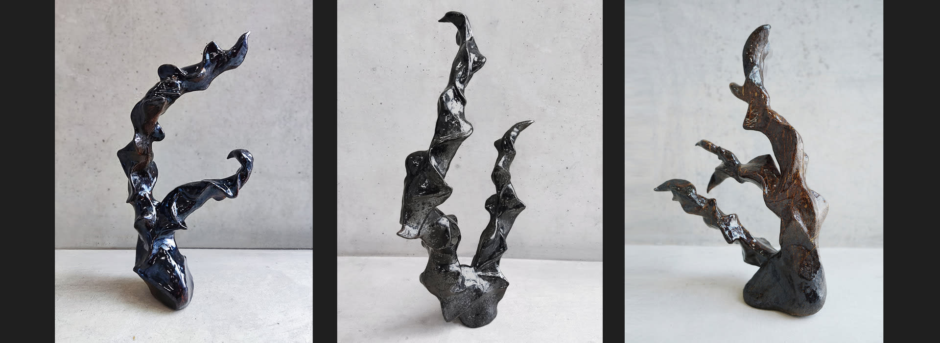 A group of fluid sculptures with dark mirror glazes