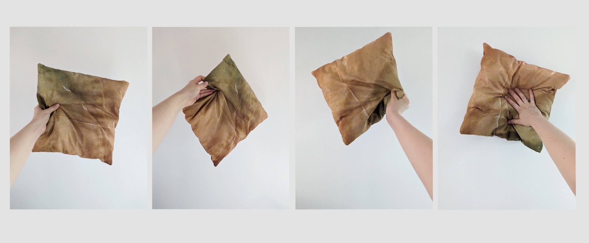 Four orange and blue hued cushions, held in the air by a white woman's hand.