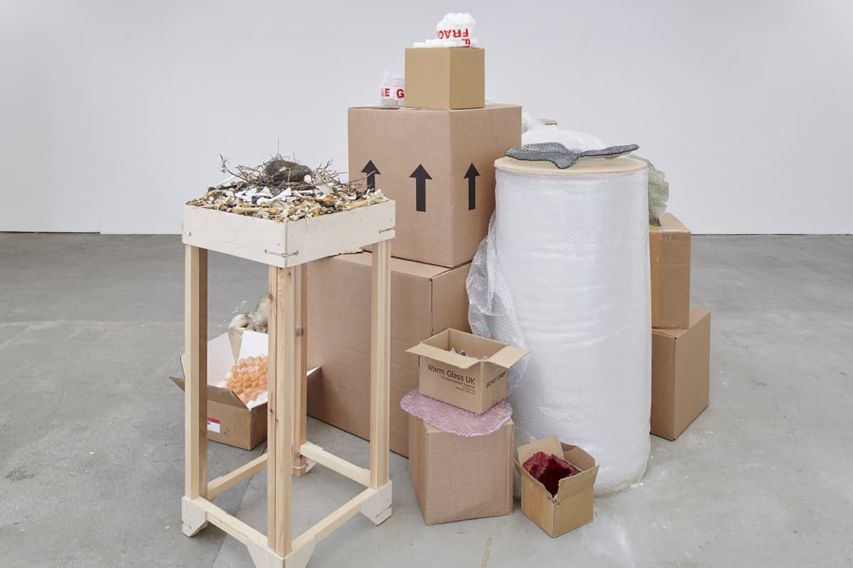 pile of cardboard boxes act as plinths to glass bubble wrap pieces adn glass filled ball of wire restricted glass  