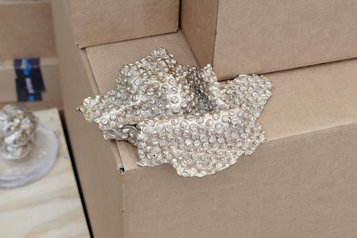 gold plated bronze bubble wrap sits on the edge of a cardboard box
