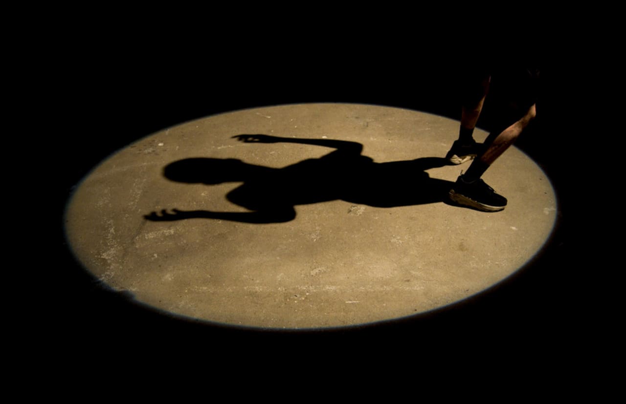 a shadow of a figure cast by a circular spotlight