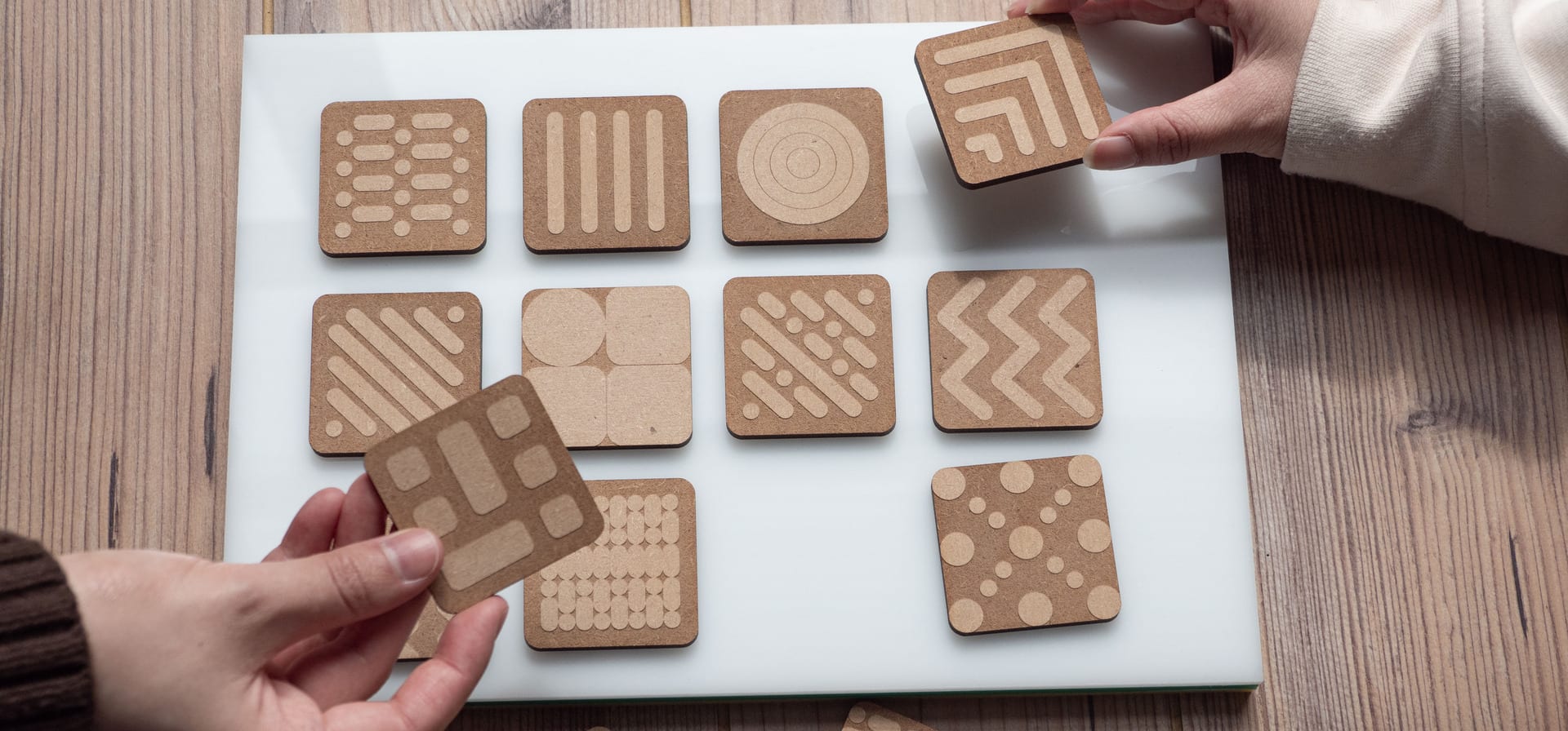 Top angle, close-up image of hands using tiles on a board 