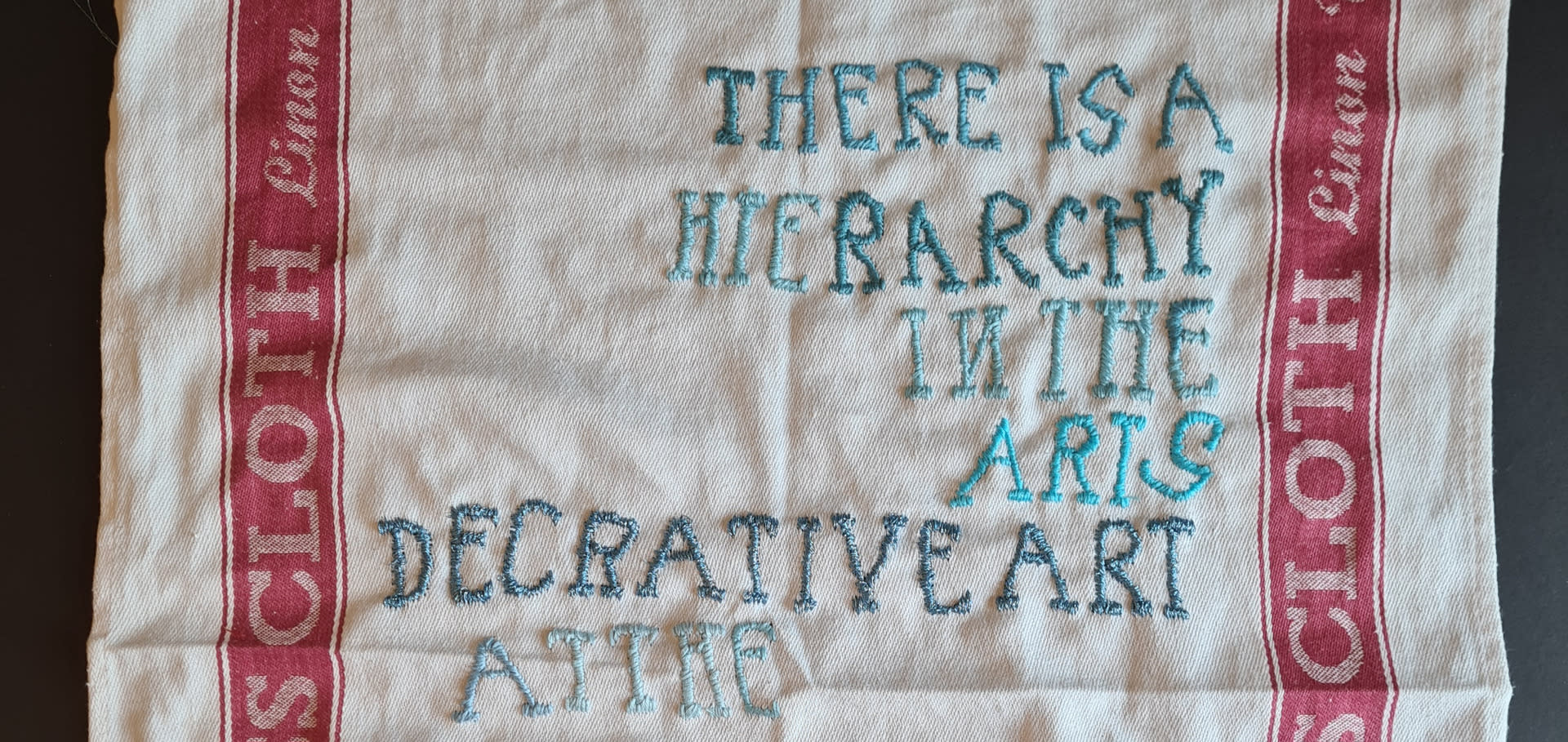 Social Fabric (heirarchy) (2023) stitch on linen/cotton-blend glass cloth, wooden clothes pegs, yarn (H) 710mm(W) 510mm