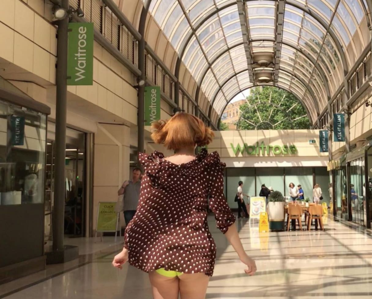 Friederike, running into position in a shopping mall, pre-recording of the re-enactment she is about to film. 