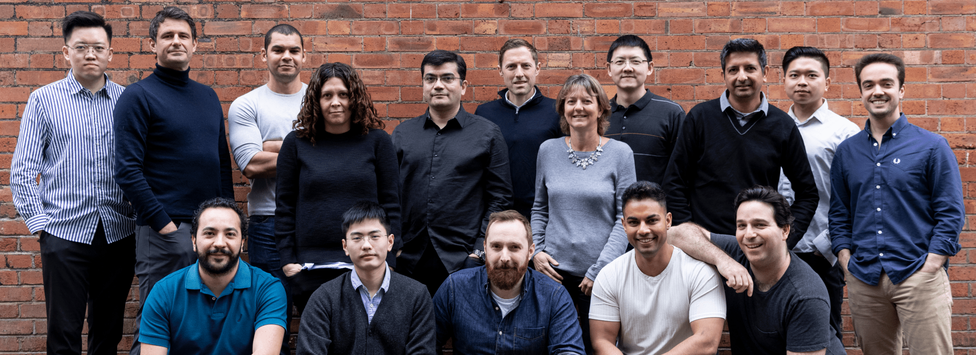 Image of the whole team stood in front of a brick wall