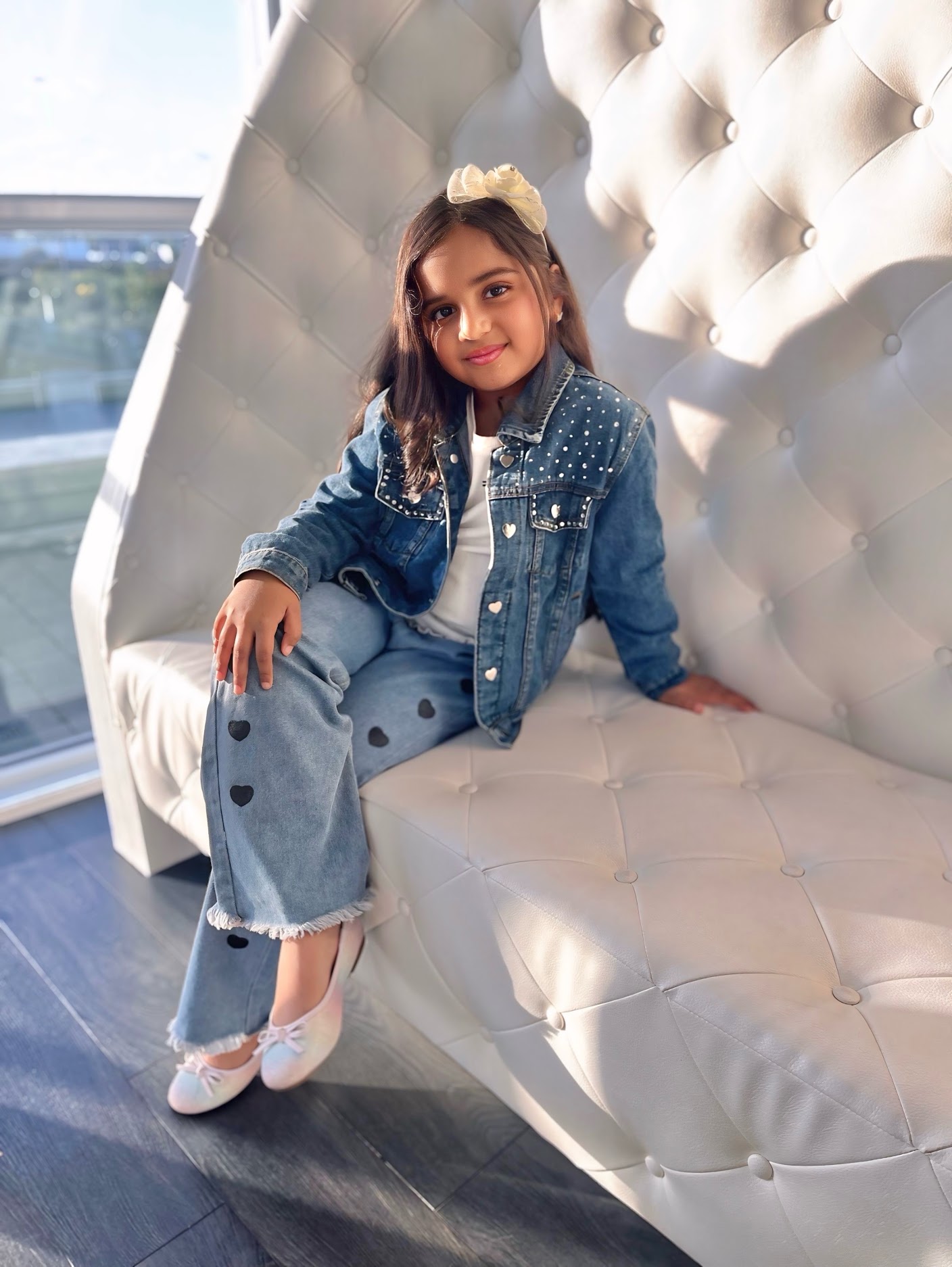 Natasha Martin smiling in denim, seated on a white chair