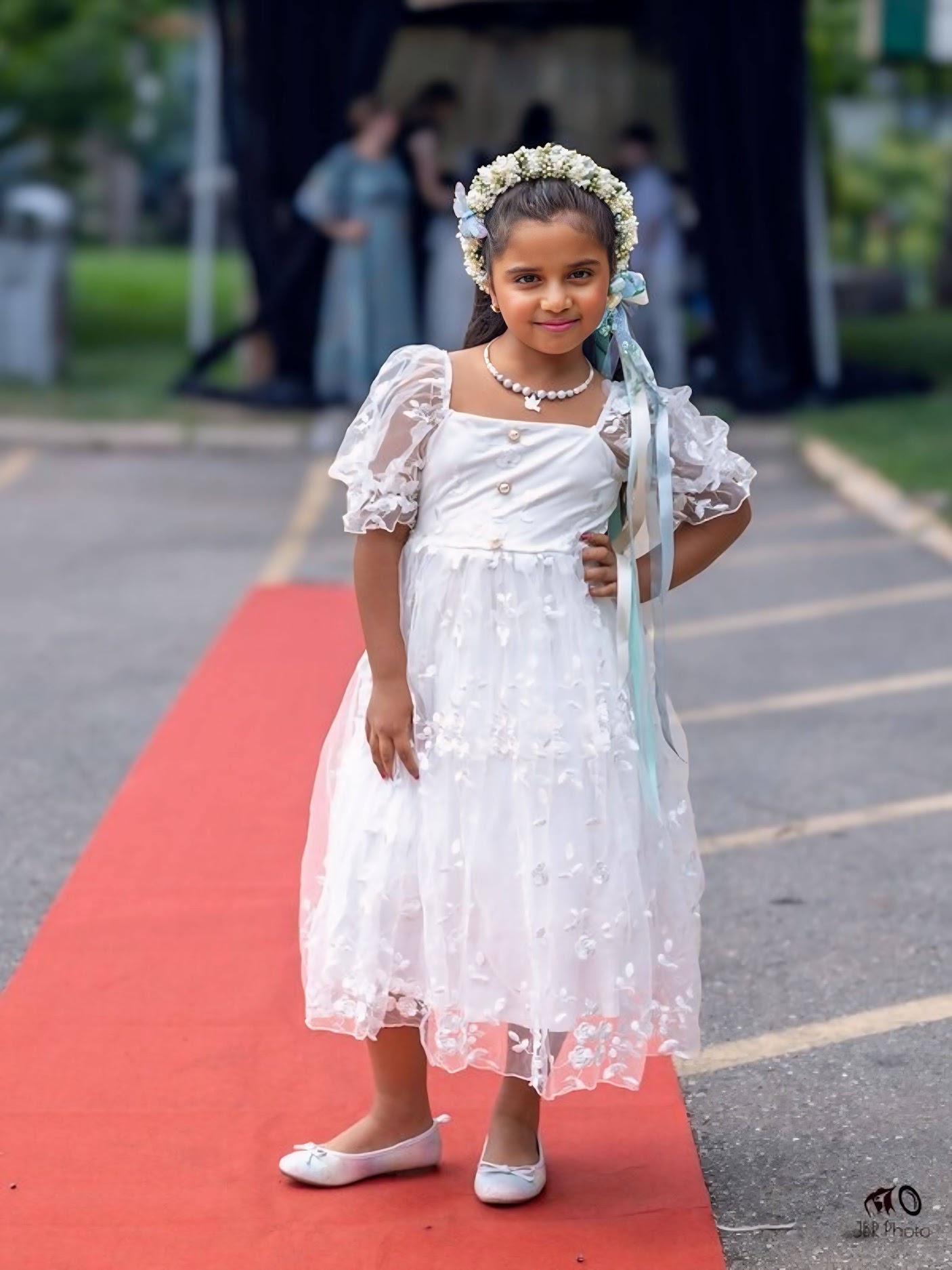 Natasha on a red carpet in a white dress