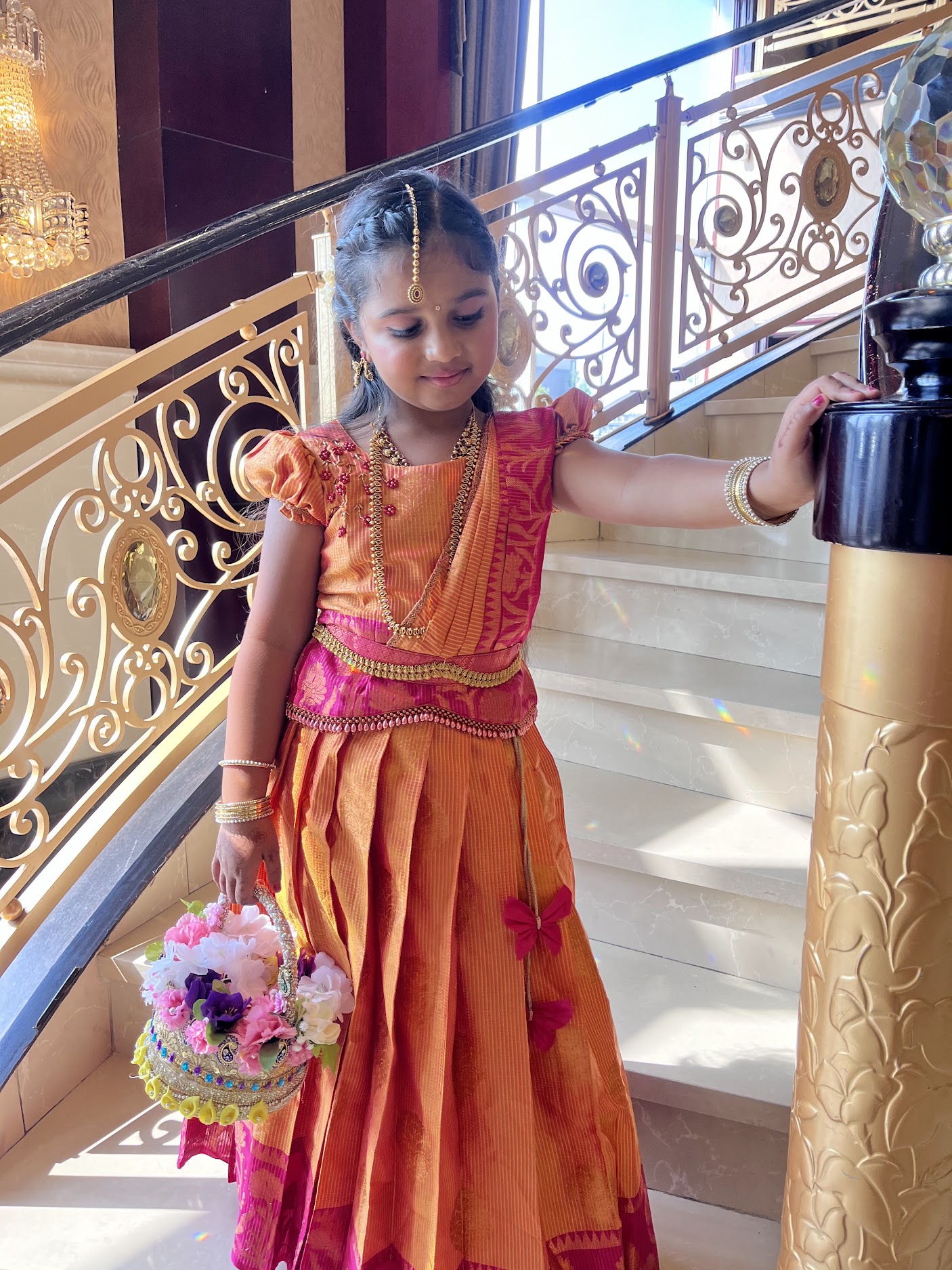 Natasha in a colourful traditional outfit beside a staircase