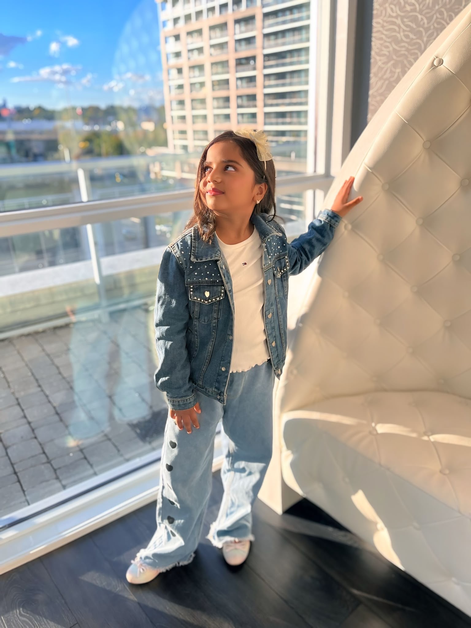 Natasha standing by a window in her denim outfit