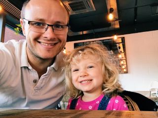 A father and his daughter take a selfie in a coffee shop. 