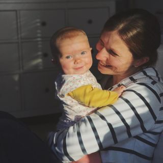 A mother in a stripy top holding a small baby