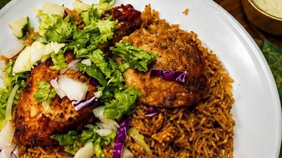 Savoury pulao topped with fried chicken and fresh salad