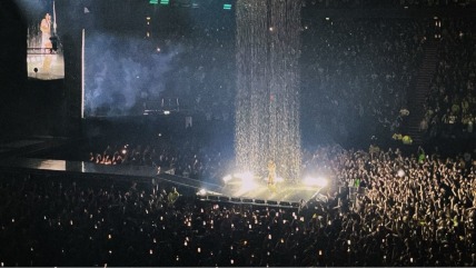 Charli xcx singing on stage under an artificial rainfall