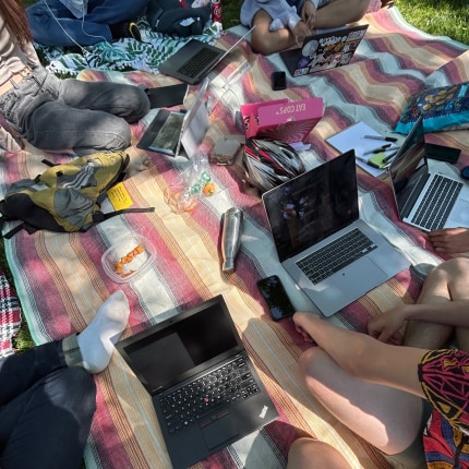 laptops on top of a striped blanket in the park