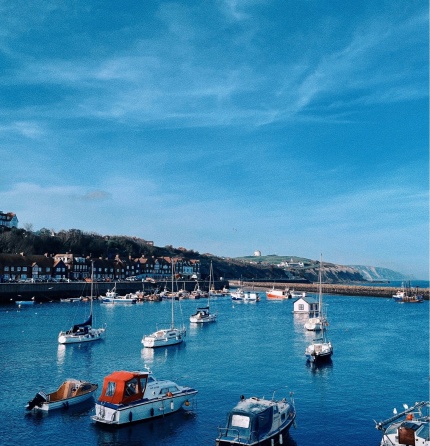 Harbour with small fishing boats and speedboat, as well as a little floating house.