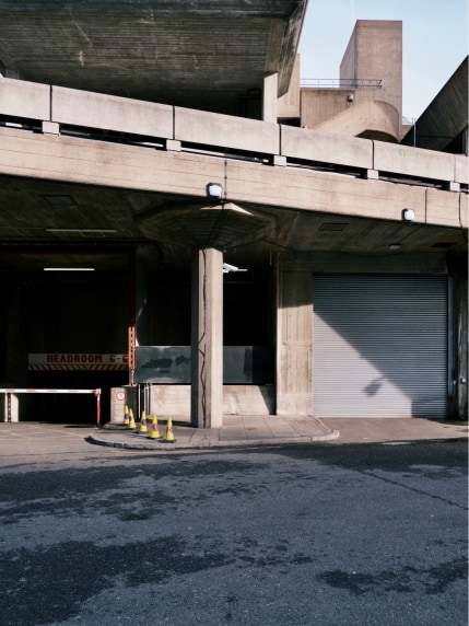 Back entrances to the Southbank centre in London, United Kingdom. The shot is of the light and shadow playing across the concrete. Yellow traffic cones pop out against the grey of the concrete.