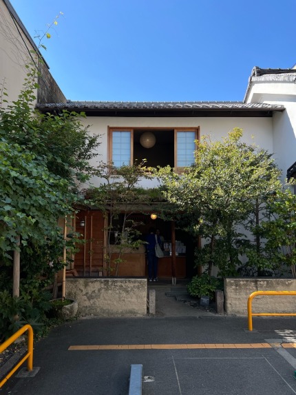 Entrance to a 2-floor coffee bar that looks like a traditional Japanese townhouse. Landscape of small trees is seen before you can enter the small cafe