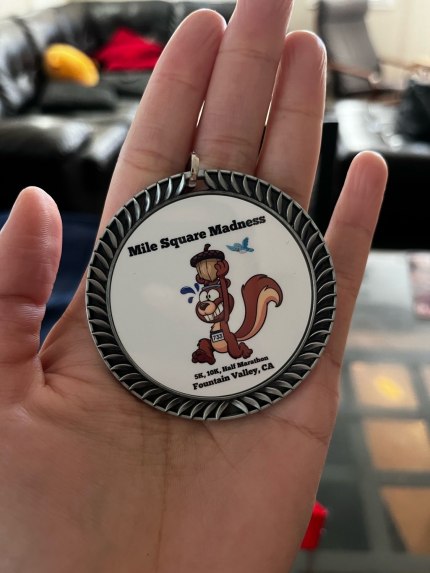 race medal with an image of a running squirrel carrying an acorn