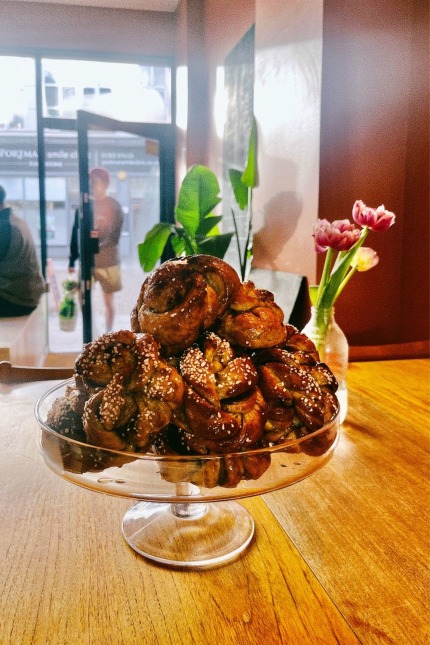 Glazed swedish buns stacked high on a glass tray in a cafe