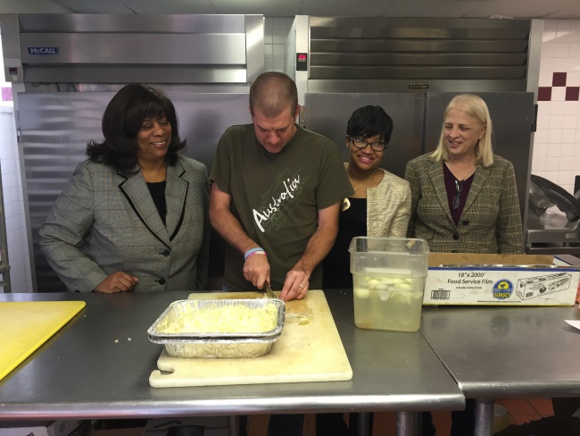 Food is being chopped in the Cass Community Services kitchen by a volunteer, pictured by Alberta Tinsely-Talabi, Michigan State Representative, LaTanya Garrett, Michigan State Representative and the Rev. Faith Fowler, Executive Director, Cass Community Social Services