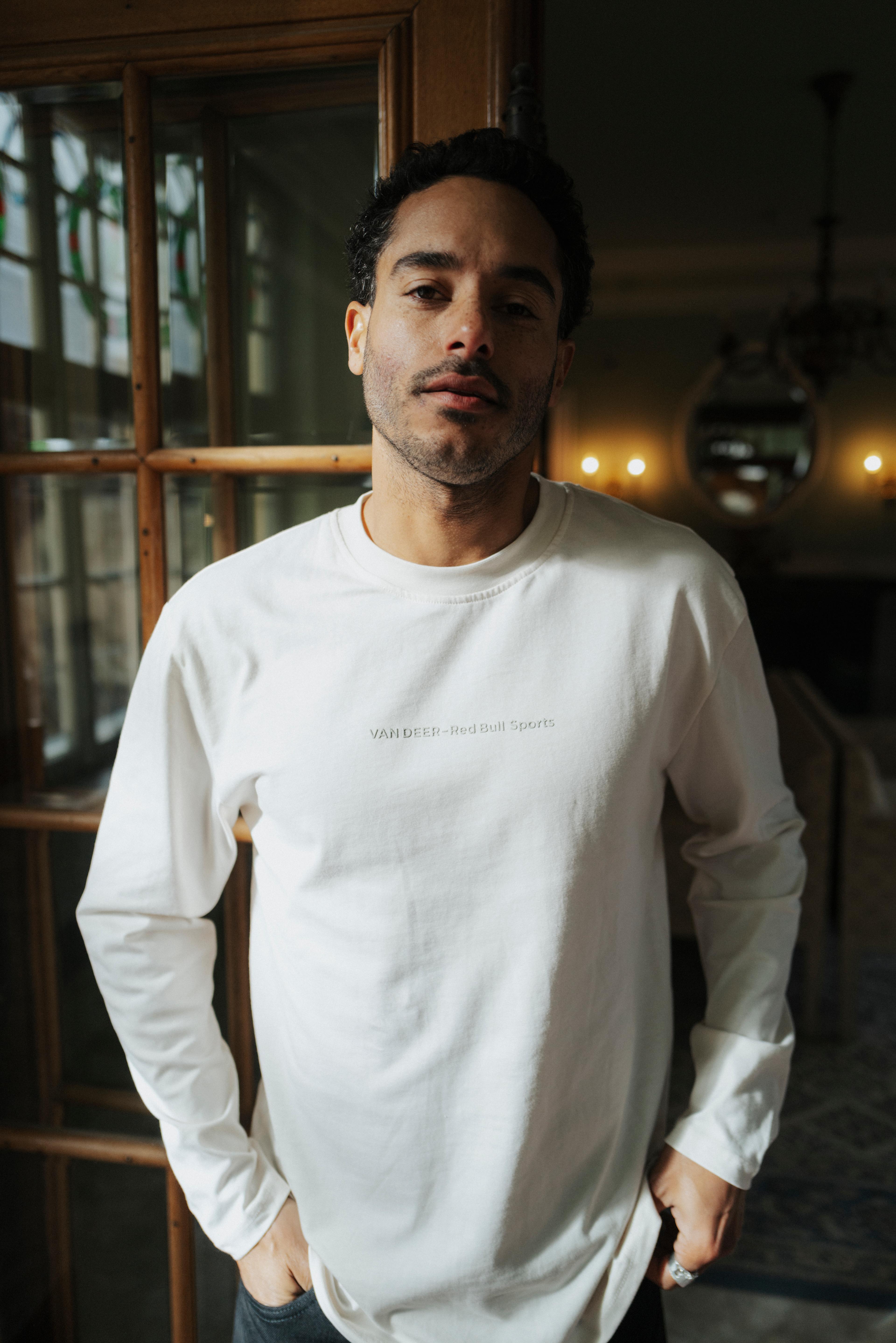A man is wearing the off-white VAN DEER-Red Bull Sports longsleeve featuring the VAN DEER brand name on the front.