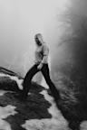 Black-and-white photo of a woman walking across a snow-covered meadow. She is wearing a VAN DEER-Red Bull Sports hoodie.