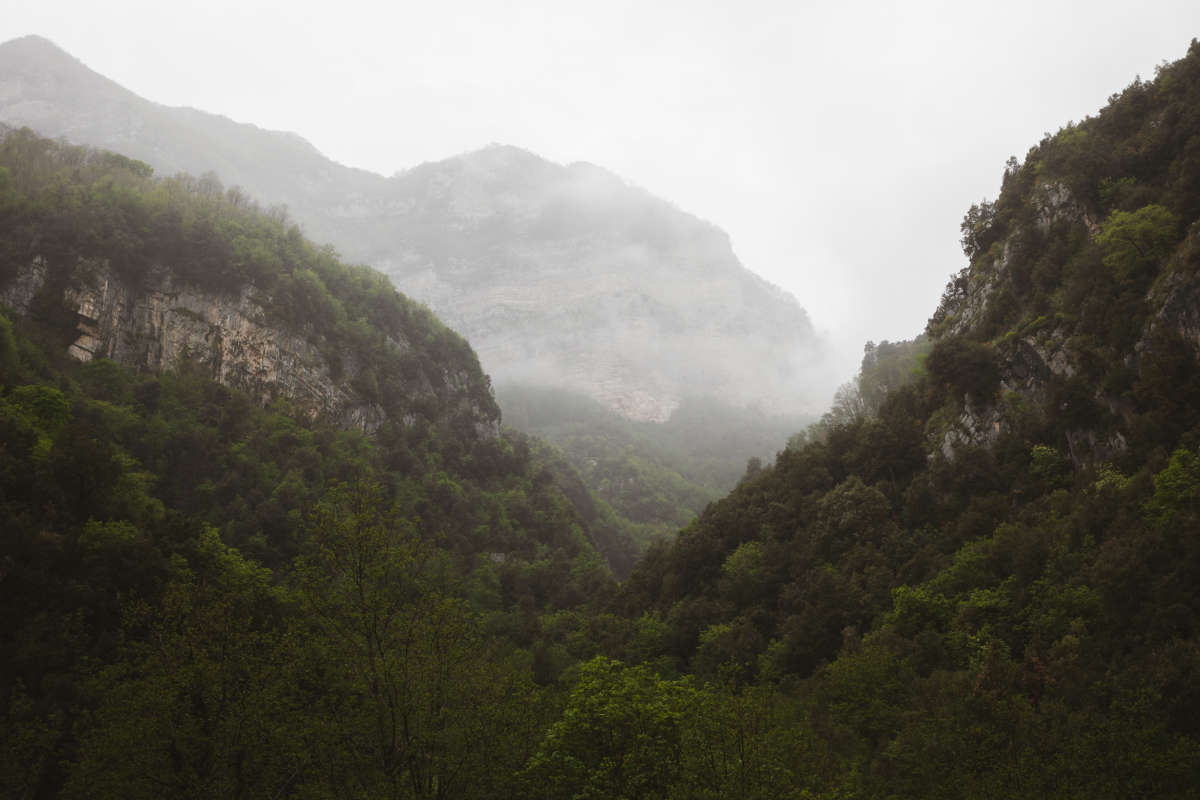 First view from the path, the valley lies under the mountains, hidden in the forest