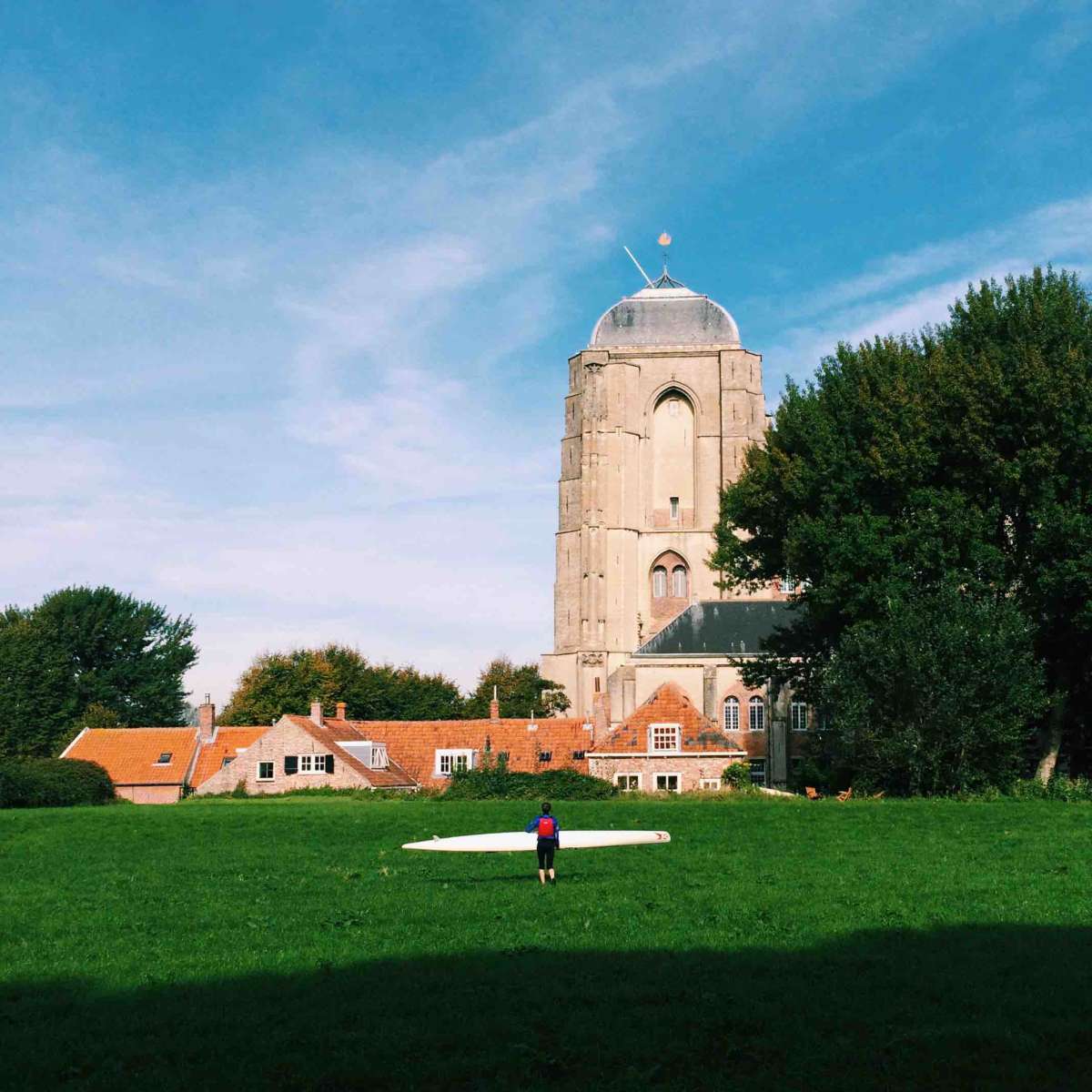 A surfer walks towards Veere’s Sancta Maria Church.  