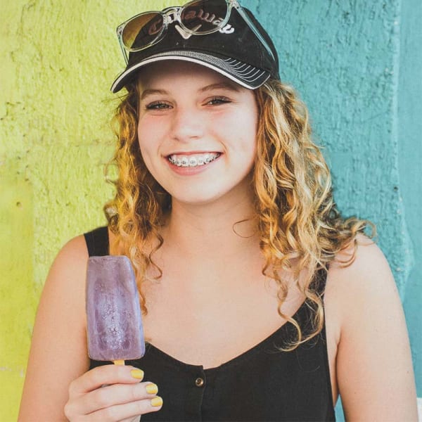 Teen eating a popsicle to sooth discomfort from her metal braces