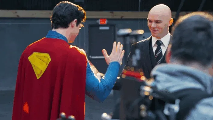 a full-body shot of a man in his suit and cape, looking upwards with a bright light behind him.