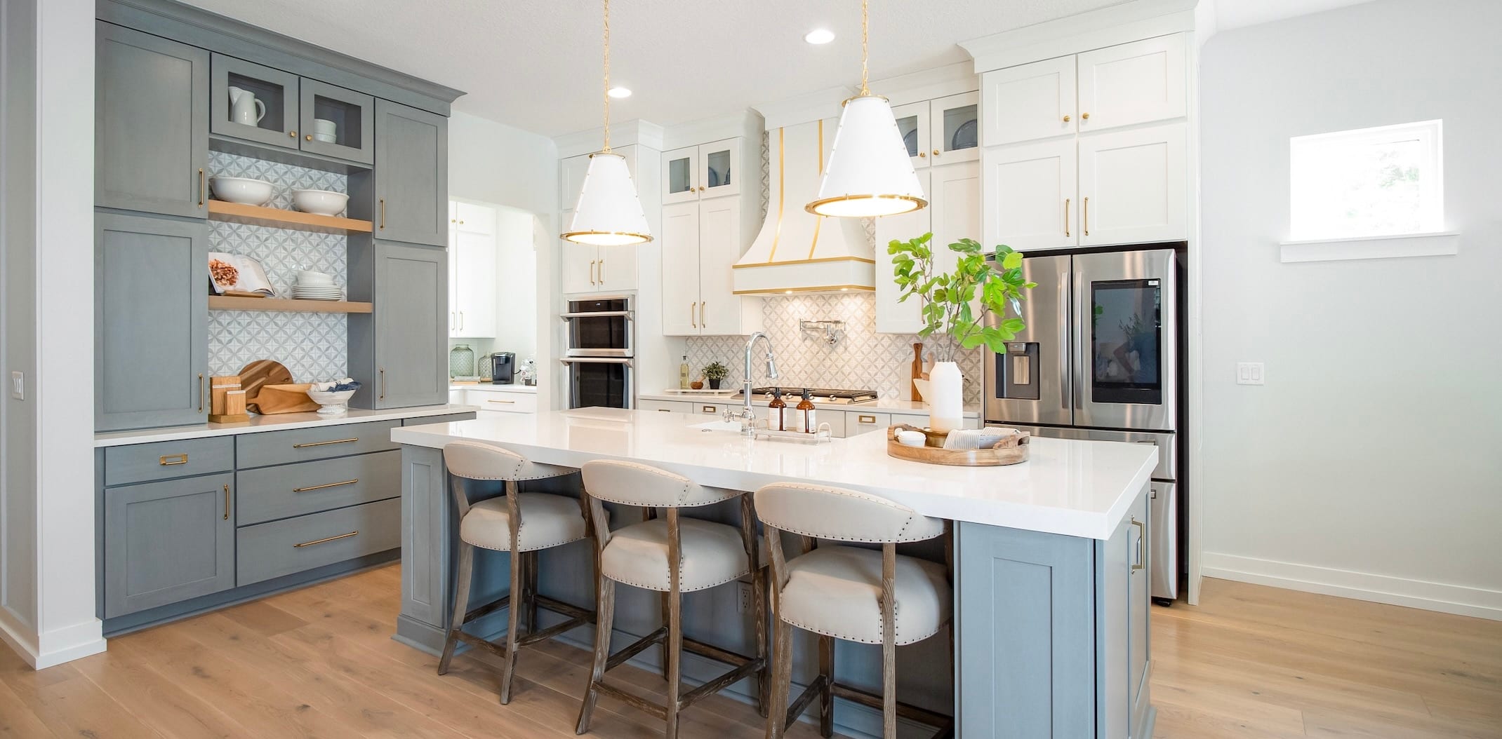 Luxury kitchen with blue cabinets, silver appliances and light colored walls.