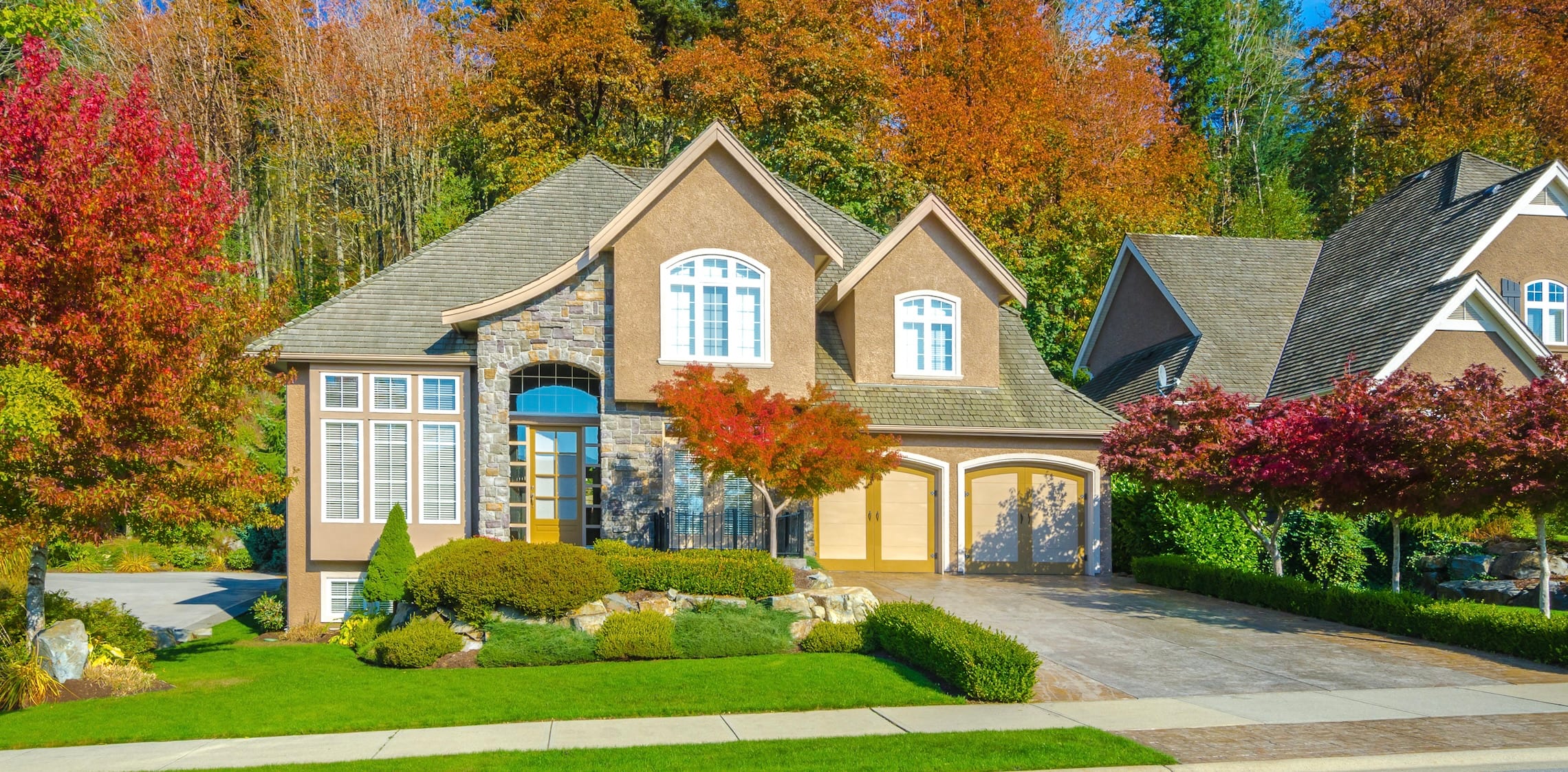 Brown house with foliage and green grass during fall.
