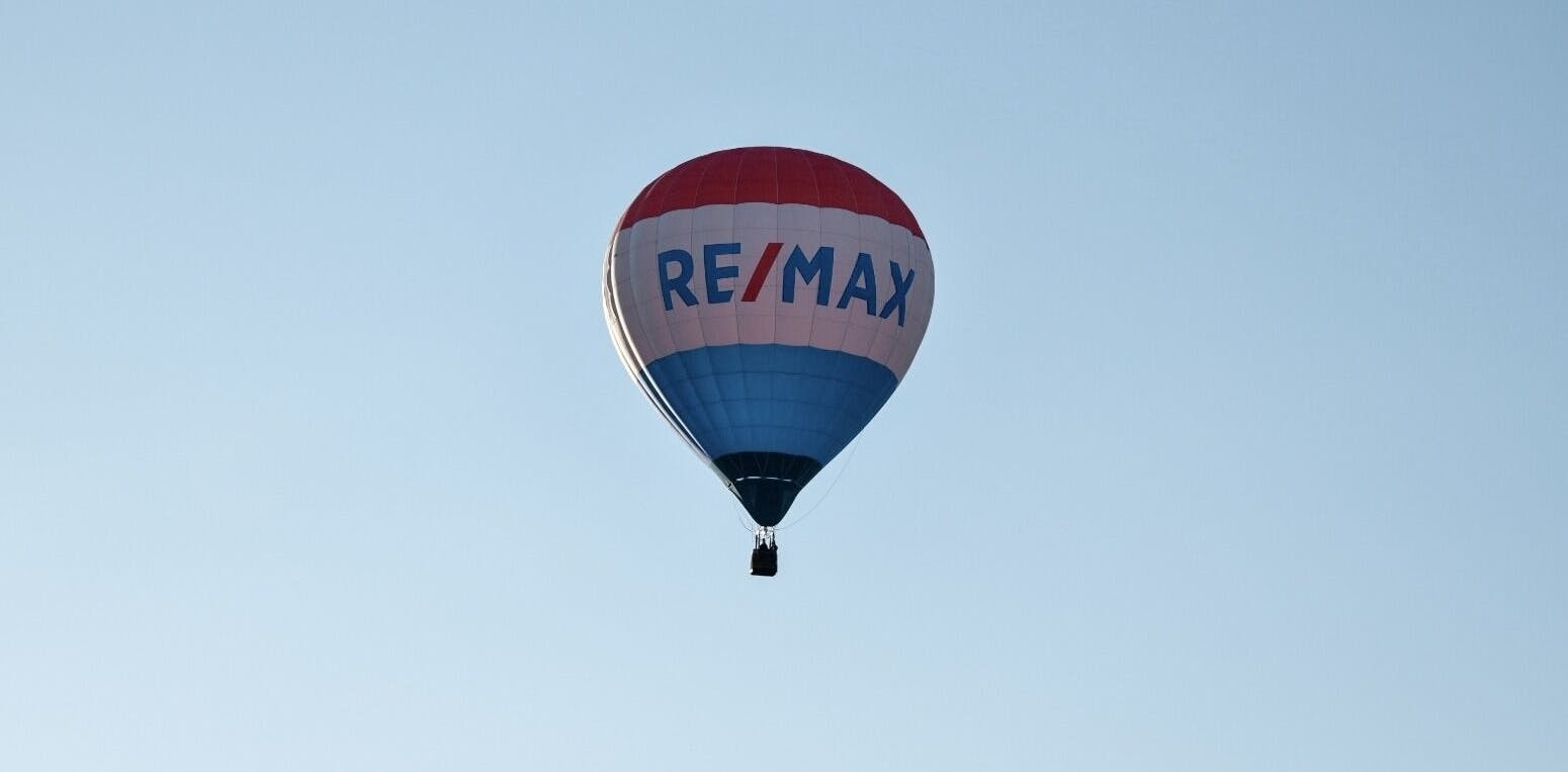 RE/MAX hot air balloon against a light blue sky.