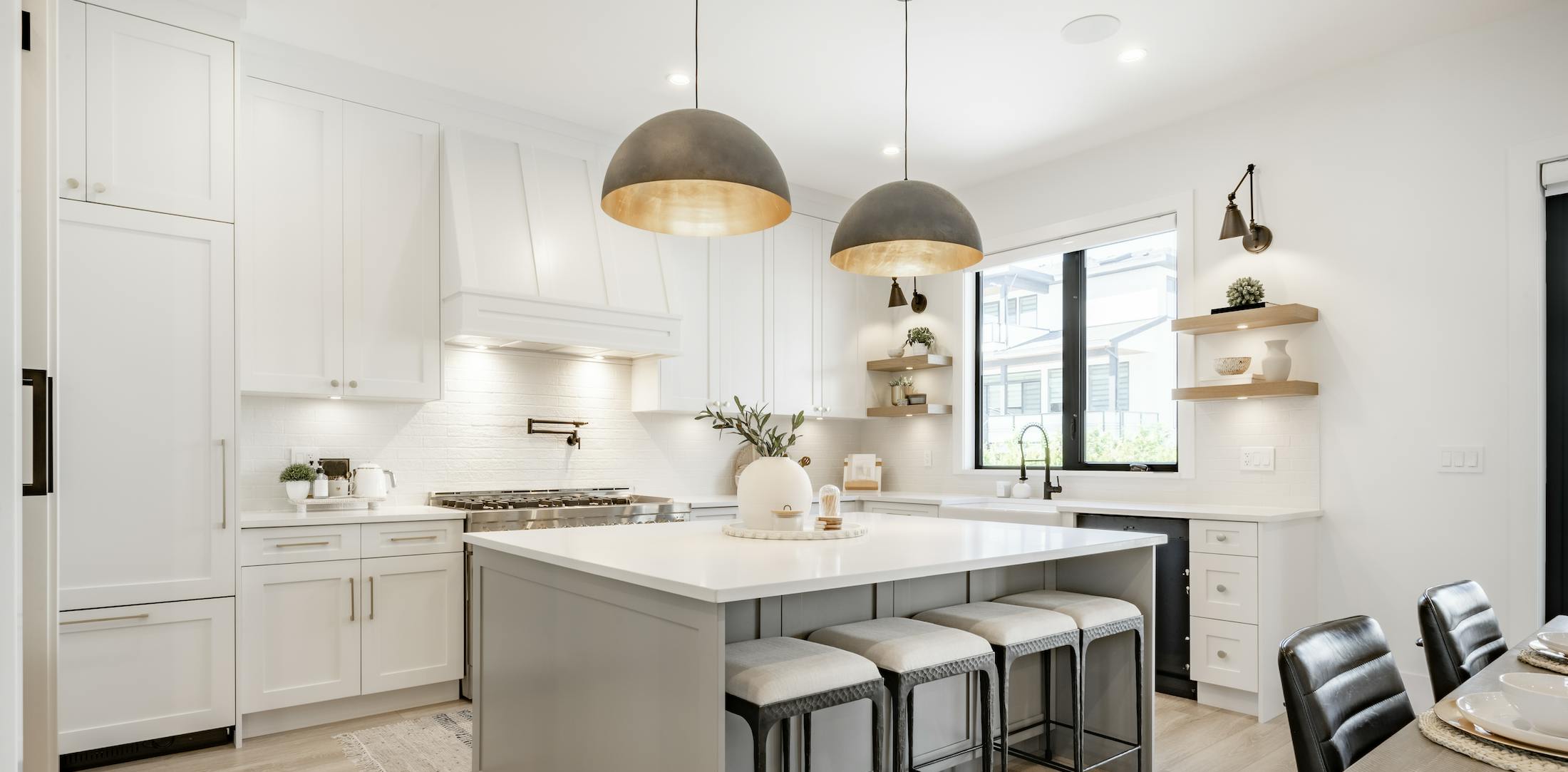 Bright kitchen with white cabinets, a grey island, and large overhead lights