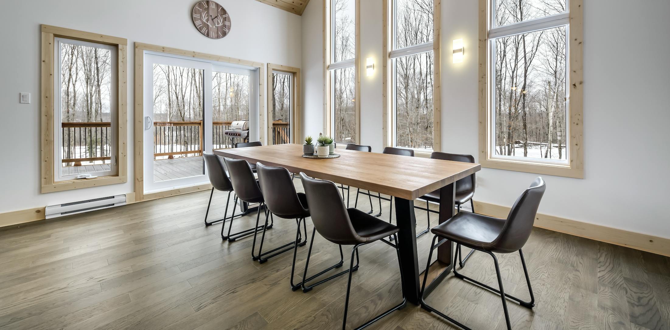 Kitchen table and chairs in room with wood floors tall ceilings, white walls, and big windows
