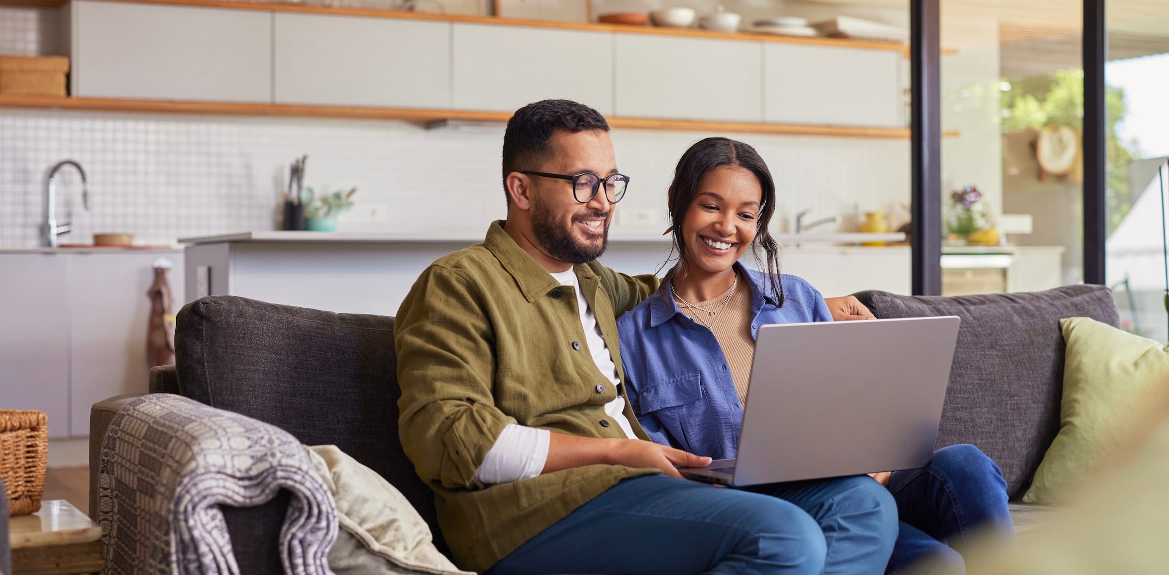 Two people sitting on a couch using a computer