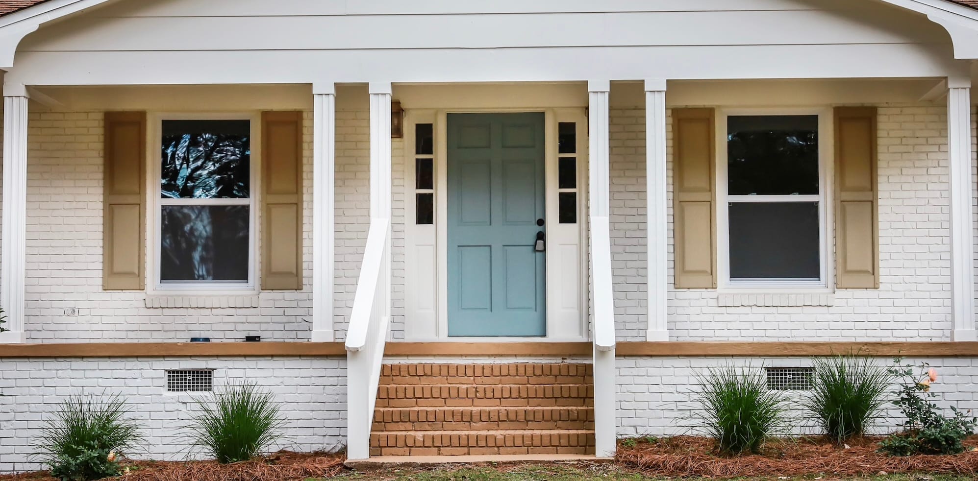Blue Door House White house with tan shutters and a blue front door.