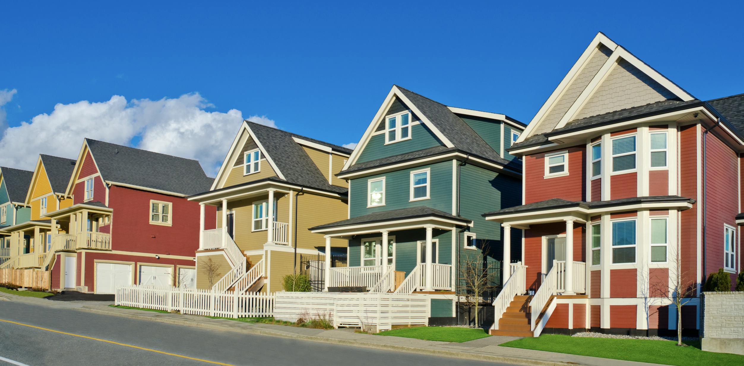 Red, green, and yellow house lined up along a street