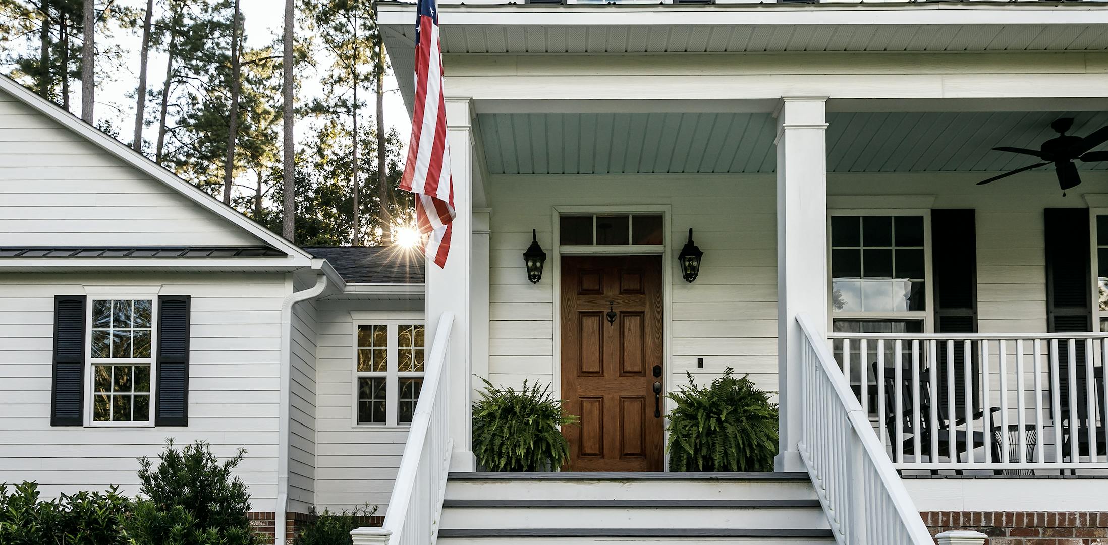 Farm house painted white with black shutters and an American flag hanging outside