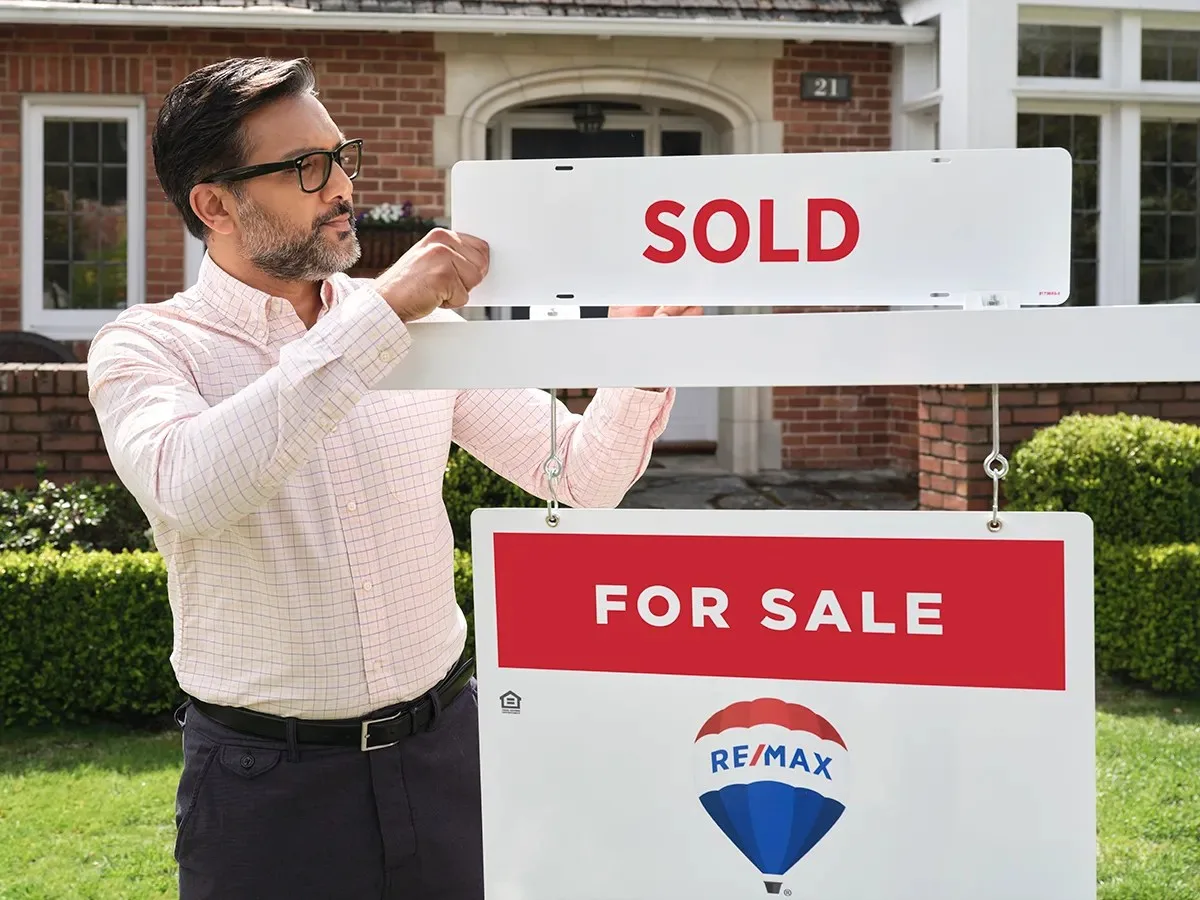 man placing sold sign
