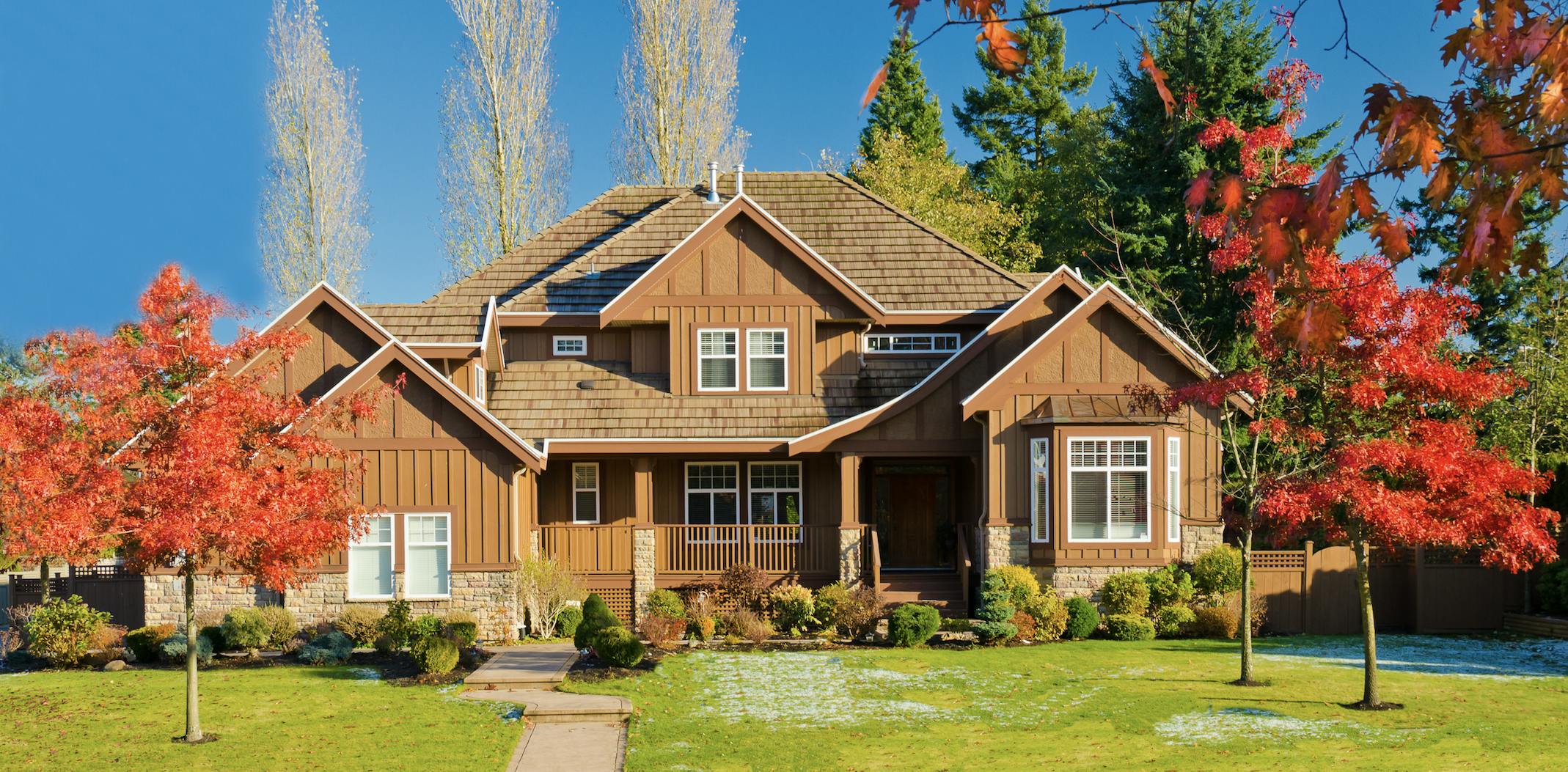 Brown house with green grass and trees experiencing foliage