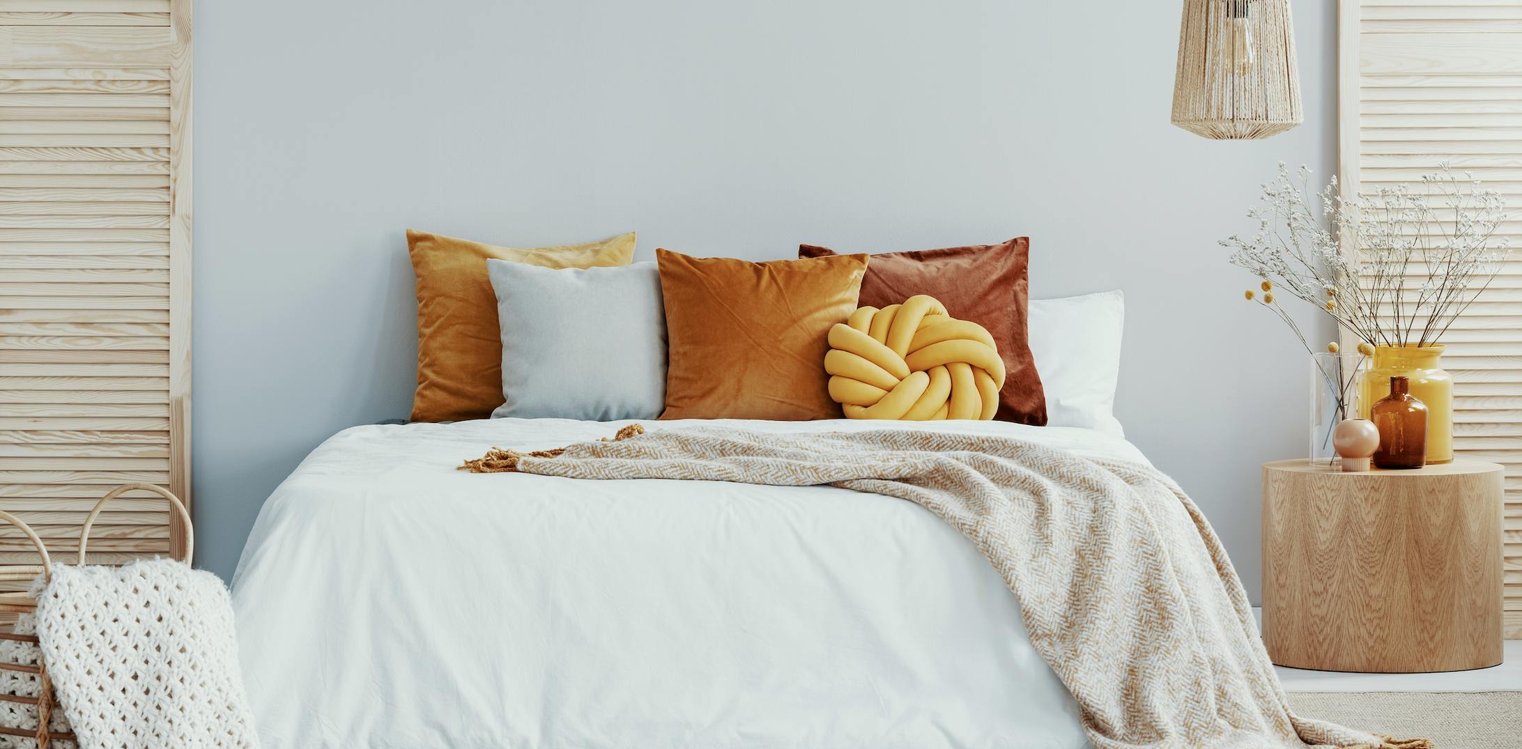Bedroom with white bed and bright orange and pink pillows.