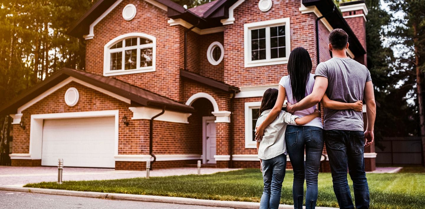 A family of three looks at their brick home