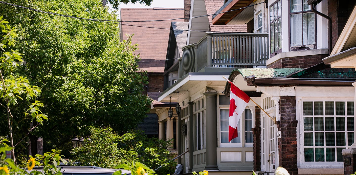 A Canadian flag hangs outside of a house