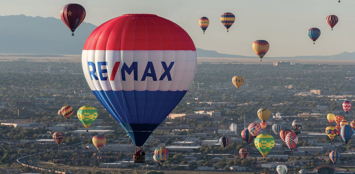 RE/MAX Hot Air Balloon and other hot air balloons over a city